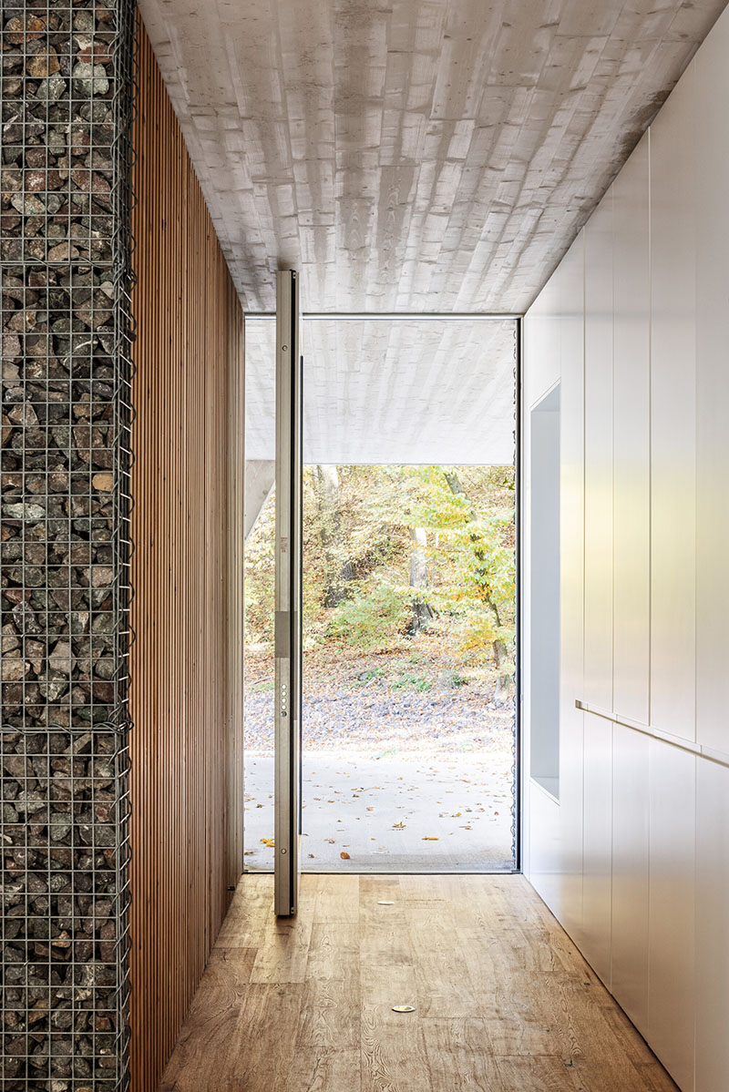 Entrada de Banánka de Paulíny Hovorka Architects con muros de gaviones y madera