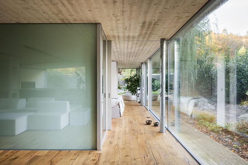 Pasillo interior de Banánka de Paulíny Hovorka Architects con panel acristalado y acceso al dormitorio