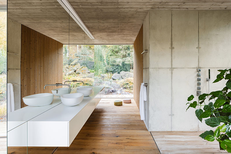 Baño de Banánka de Paulíny Hovorka Architects con muros de hormigón y lavabo suspendido frente al paisaje