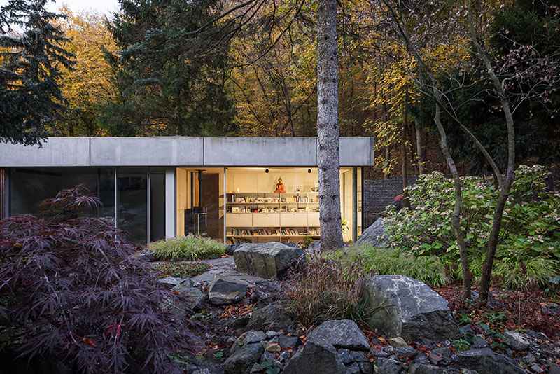 Vista de Banánka de Paulíny Hovorka Architects con interior iluminado y jardín frondoso en primer plano