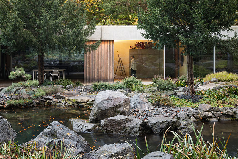 Taller acristalado de Banánka de Paulíny Hovorka Architects orientado hacia el estanque y las rocas del jardín