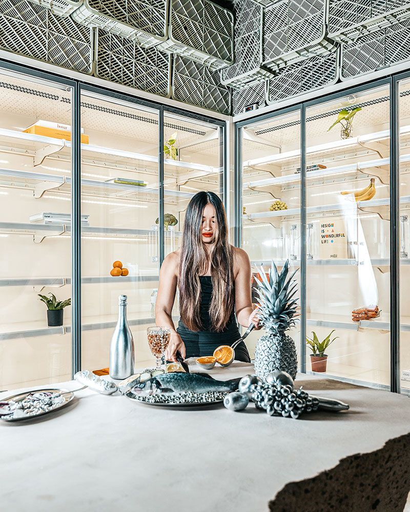 Plastic Box de Minimal Studio en Mallorca: una mujer rodeada de comida dentro del supermercado brutalista