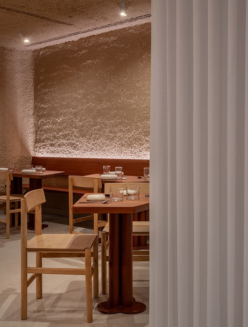 Detalle del restaurante Tándem, Murcia, proyecto de Laura Ortín con mesa y sillas de madera junto a cortina blanca