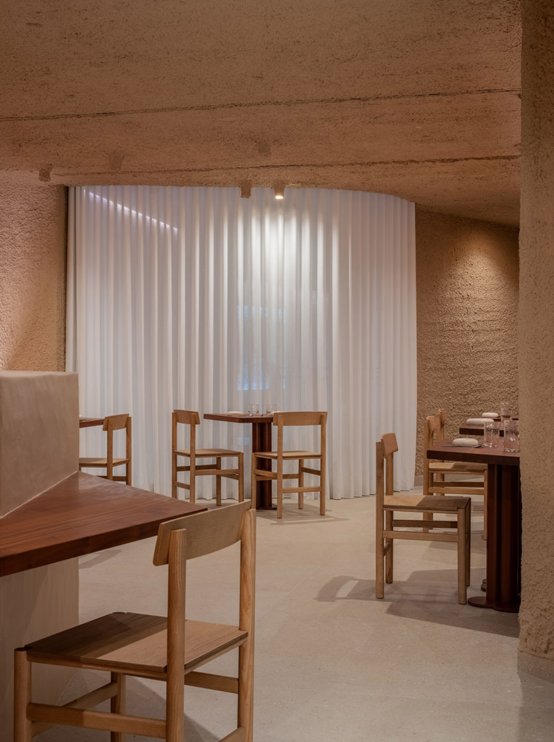 Detalle del restaurante Tándem, Murcia, proyecto de Laura Ortín con mesa y sillas de madera junto a cortina blanca
