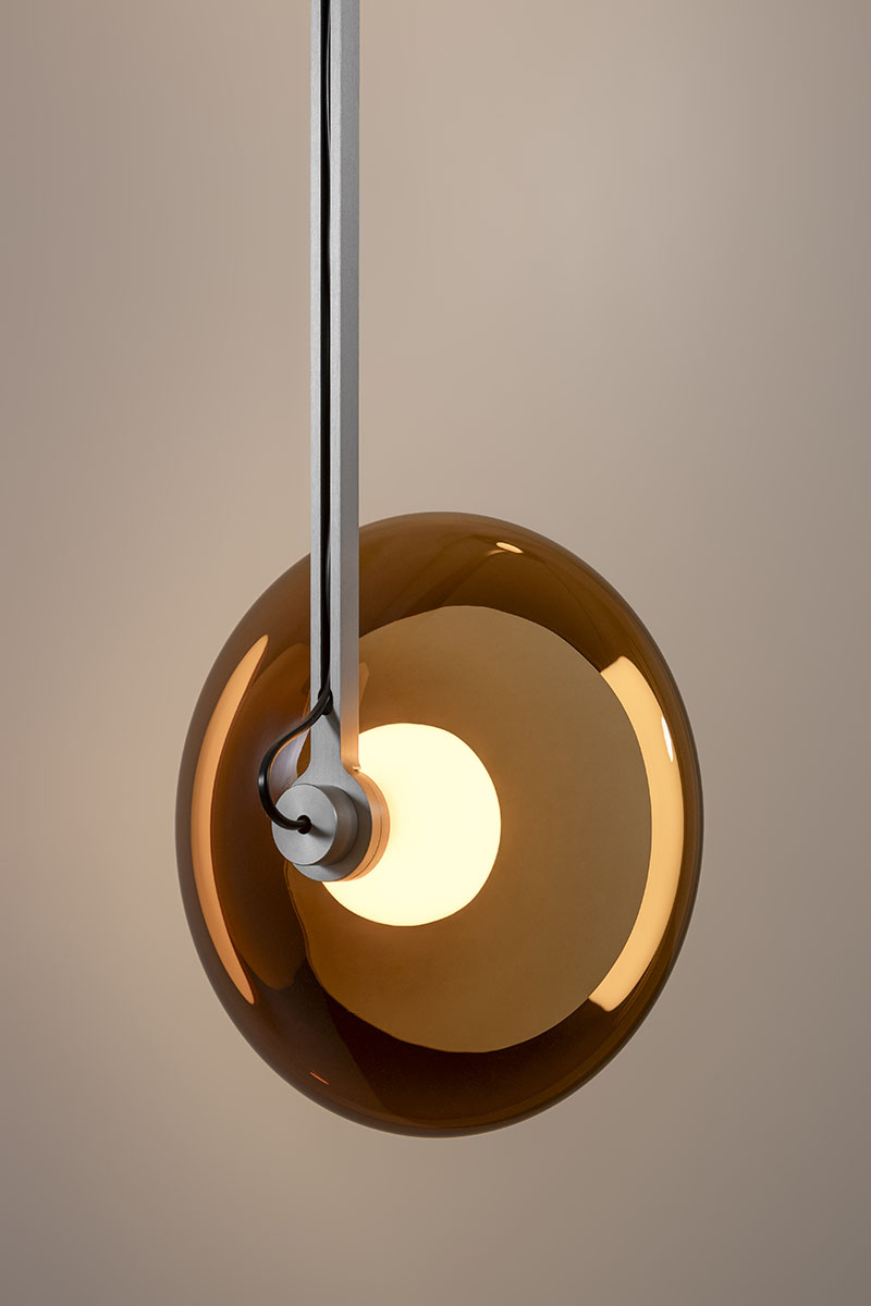 El globo ámbar suspendido de Clair-obscur de Ronan Bouroullec en la galería Kreo aparece en primer plano con su soporte metálico