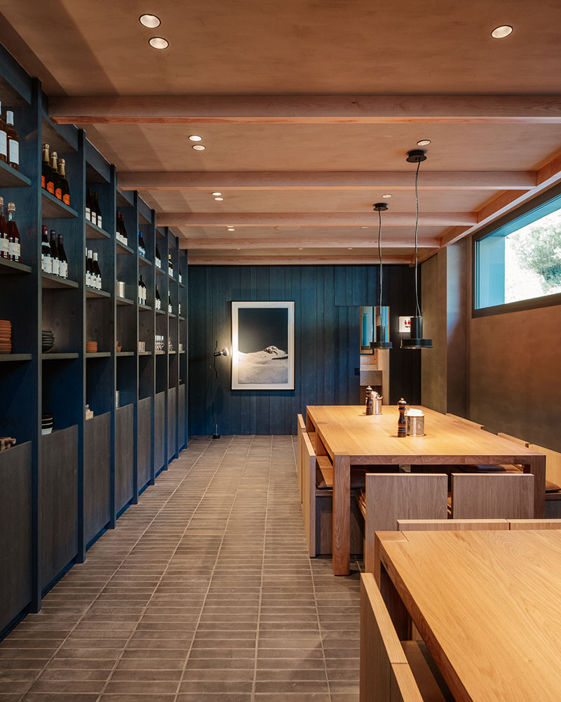 Zona de comedor con estanterías y obra fotográfica en Fora Pizza de Sandra Tarruella