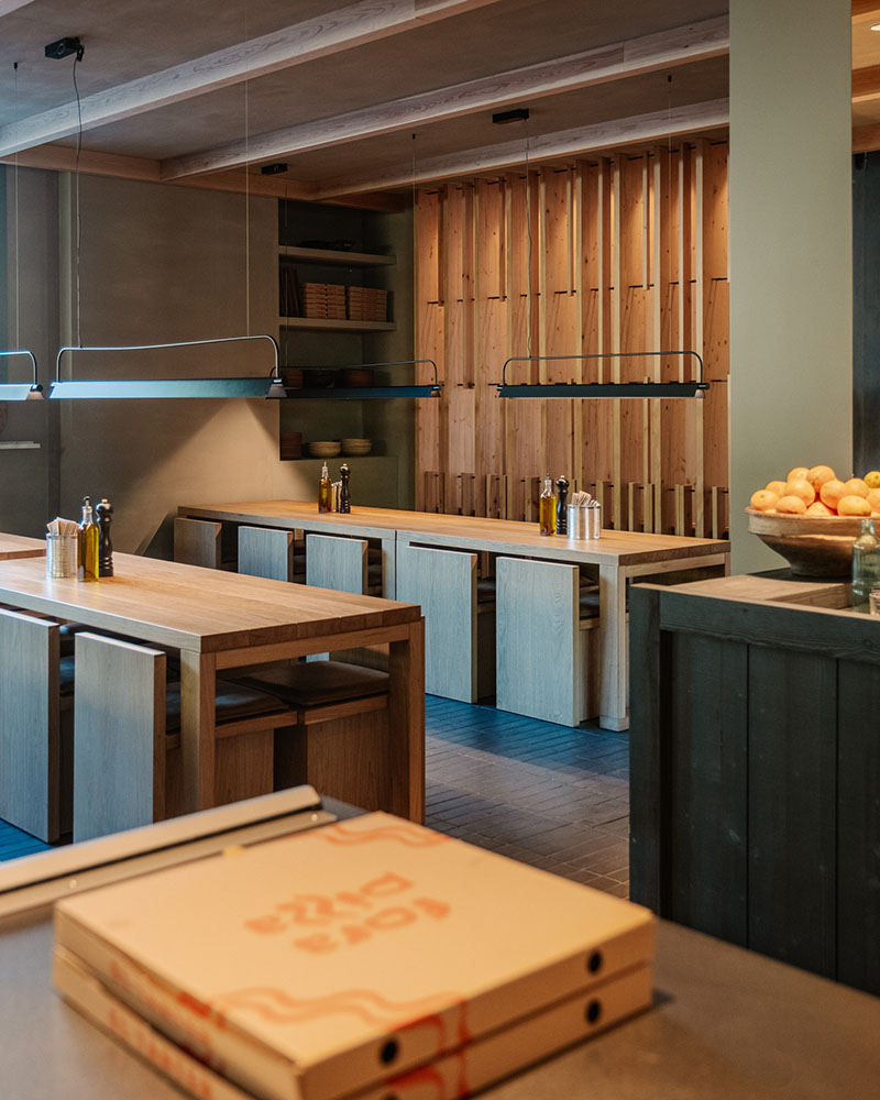 Área de comedor con cajas de pizza en Fora Pizza proyectado por Sandra Tarruella