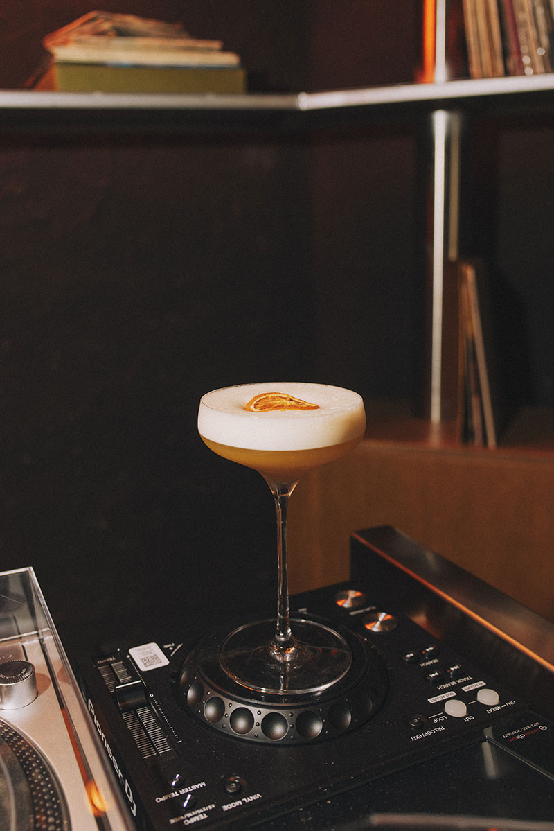 Copa de cóctel servida en Snake Bar Madrid sobre equipo de música