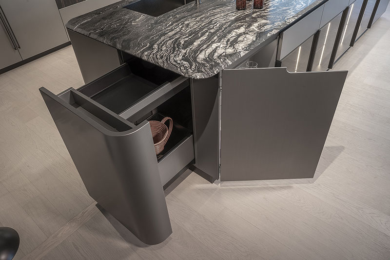 Detalle de la cocina metálica con formas curvas de Arrital, con cesto extraíble en módulo lateral