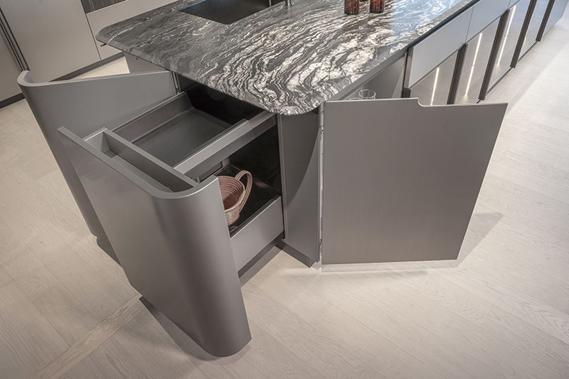 Detalle del módulo lateral de la cocina metálica con formas curvas de Arrital, con cestos interiores abiertos