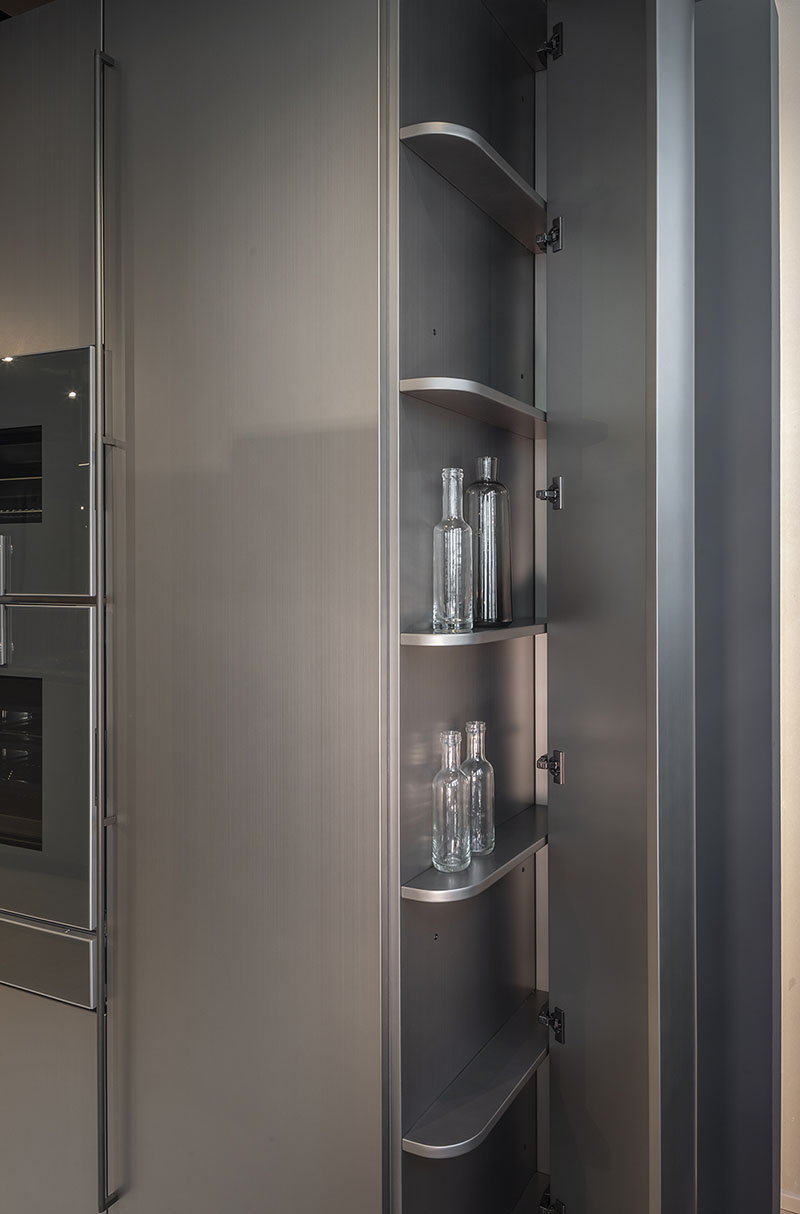 Columna auxiliar de la cocina metálica con formas curvas de Arrital, con estantes interiores curvados