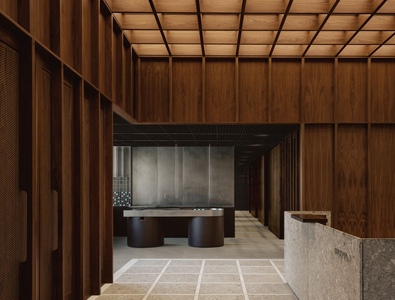 AtelierCarle Oakv: vista de la recepción con revestimientos de nogal y mostrador de piedra