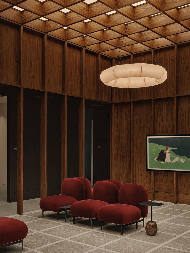 AtelierCarle Oakv: sala de espera con techo de madera, butacas rojas y luminaria circular