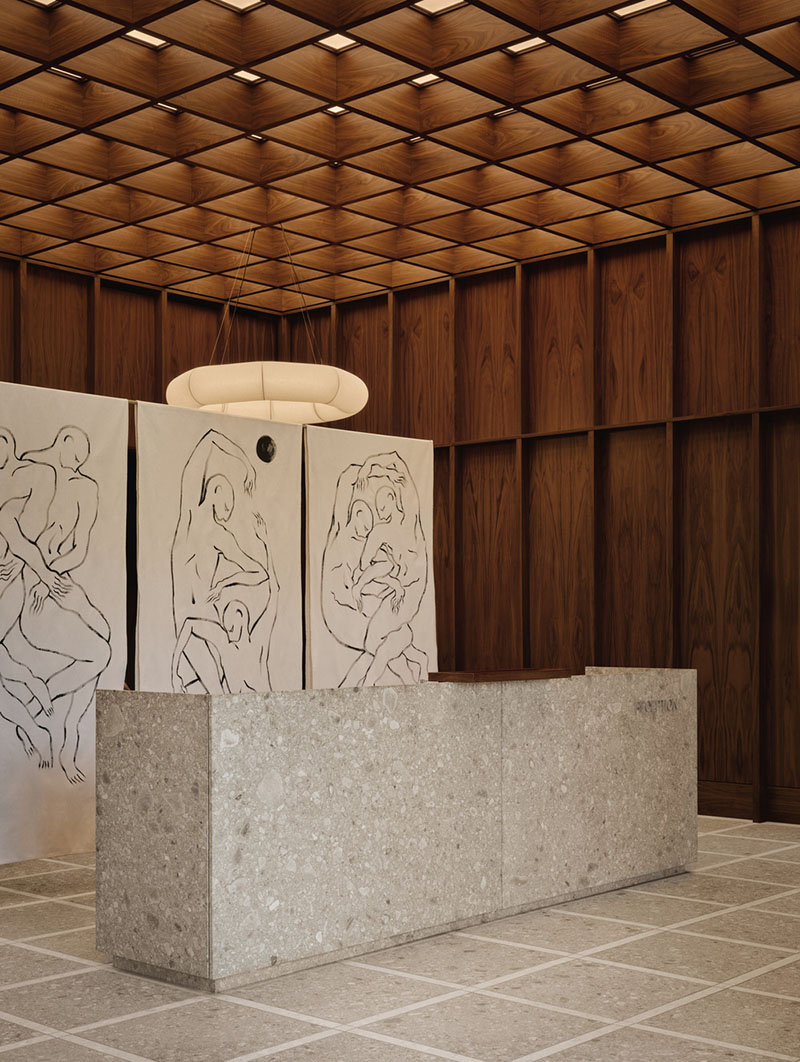 AtelierCarle Oakv: mostrador principal en piedra frente a paneles artísticos y techo de celosía de nogal