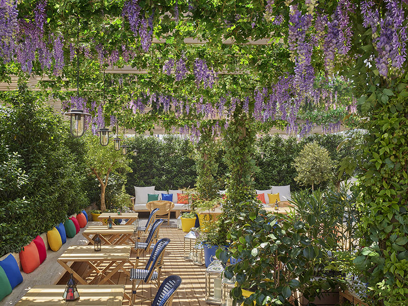 Terraza The Roof de The Madrid Edition preparada para el Brunch Oroya bajo pérgolas cubiertas de flores y vegetación