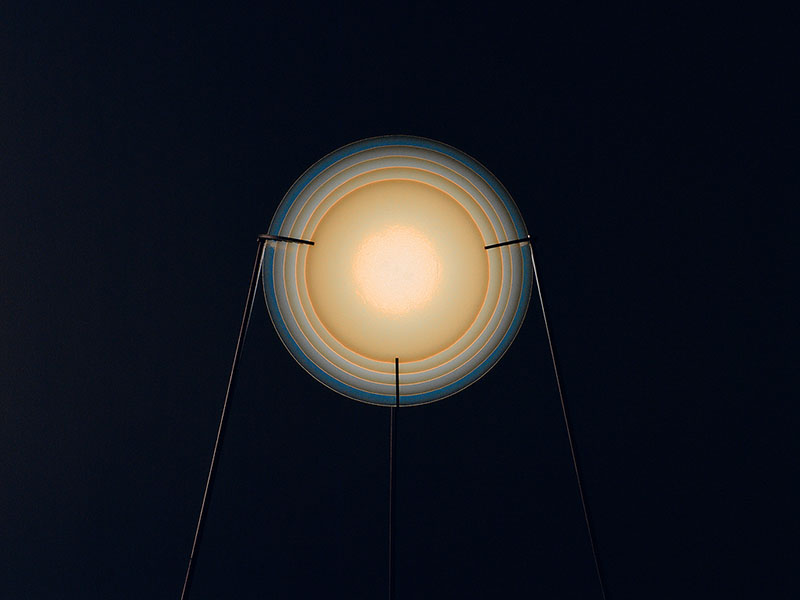 Design Beyond Things: lámpara circular encendida sobre un fondo negro.