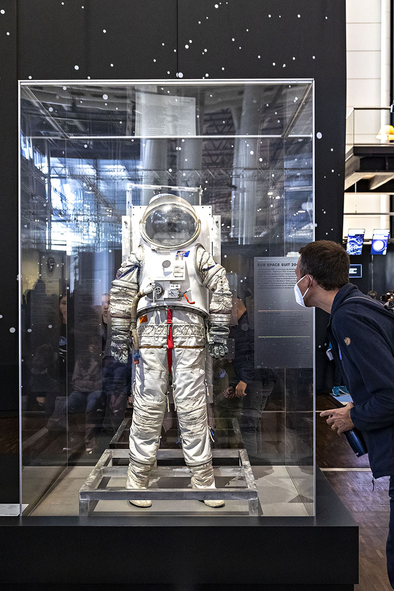 Traje espacial exhibido en la exposición Space Mission de la Cité des Sciences et de l’Industrie, frente a un visitante