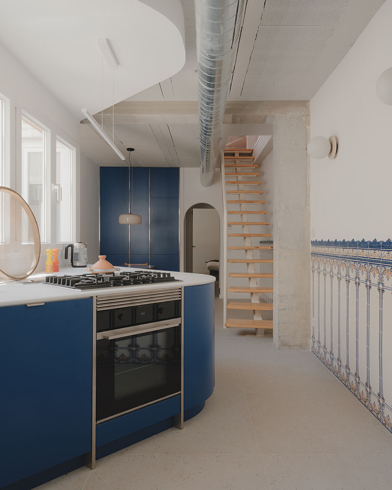 Cocina diseñada por Maria Aucejo, arquitecta, en el dúplex en Alboraia con mobiliario azul y escalera vista