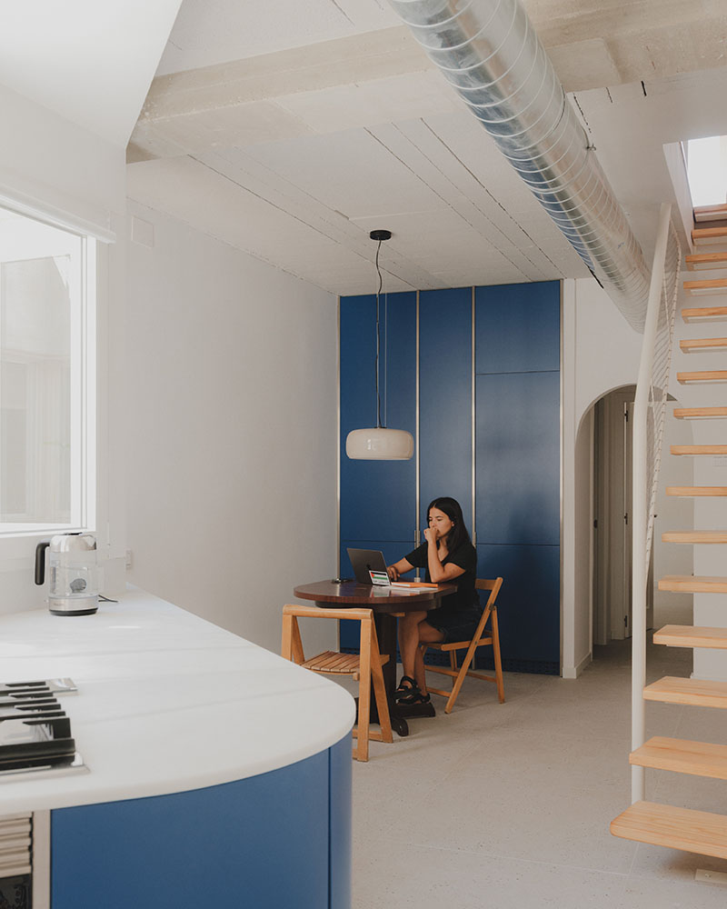 Zona de comedor proyectada por Maria Aucejo, arquitecta, en el dúplex en Alboraia con mobiliario azul y mesa redonda