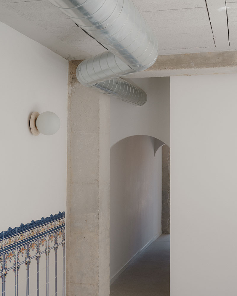 Pasillo del dúplex en Alboraia de Maria Aucejo, arquitecta, con conducto metálico visto y zócalo cerámico recuperado