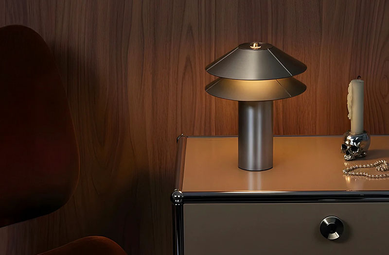 Lámpara portátil 2Shades de Minale sobre una mesilla metálica junto a una vela