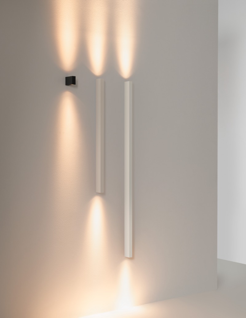Offset: pared blanca iluminada con tres lámparas de la colección Offset en distintas longitudes.