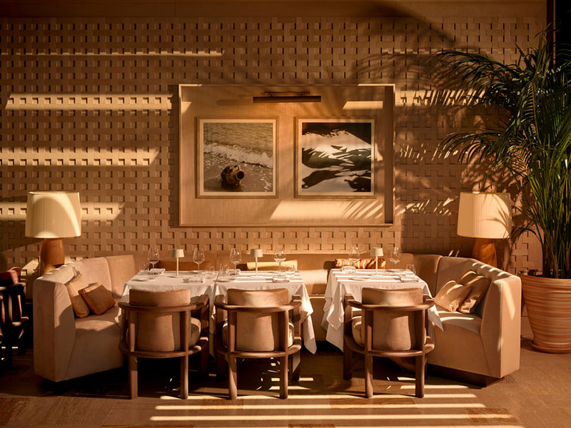 Zona de comedor lateral del restaurante Esca con muros texturados y obras fotográficas de Urbanjobs