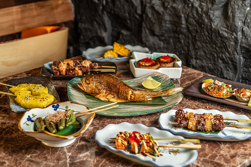 Selección de platos del restaurante Toritama Yakitori con distintas brochetas y pescado entero