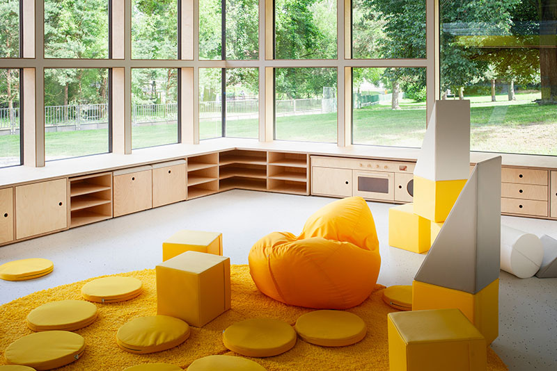 Xtopix Architekti diseña un aula con mobiliario modular en tonos amarillos y amplios ventanales al jardín