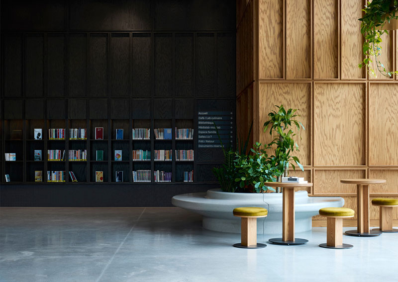 La biblioteca del Centre Sanaaq combina estanterías oscuras con zonas de asientos y vegetación interior