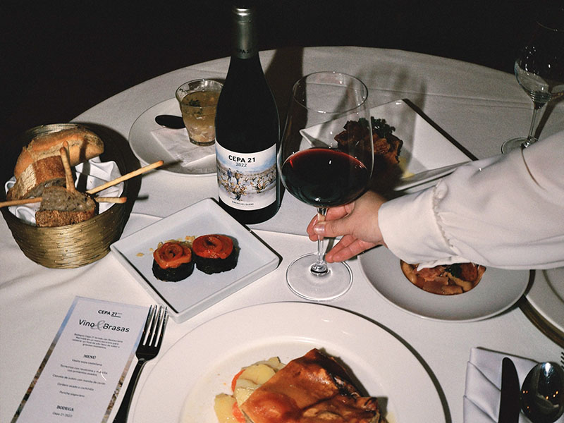 Botella de Cepa 21 y copa de vino tinto servidas en la mesa del menú tradicional de Navidad en Marmalé