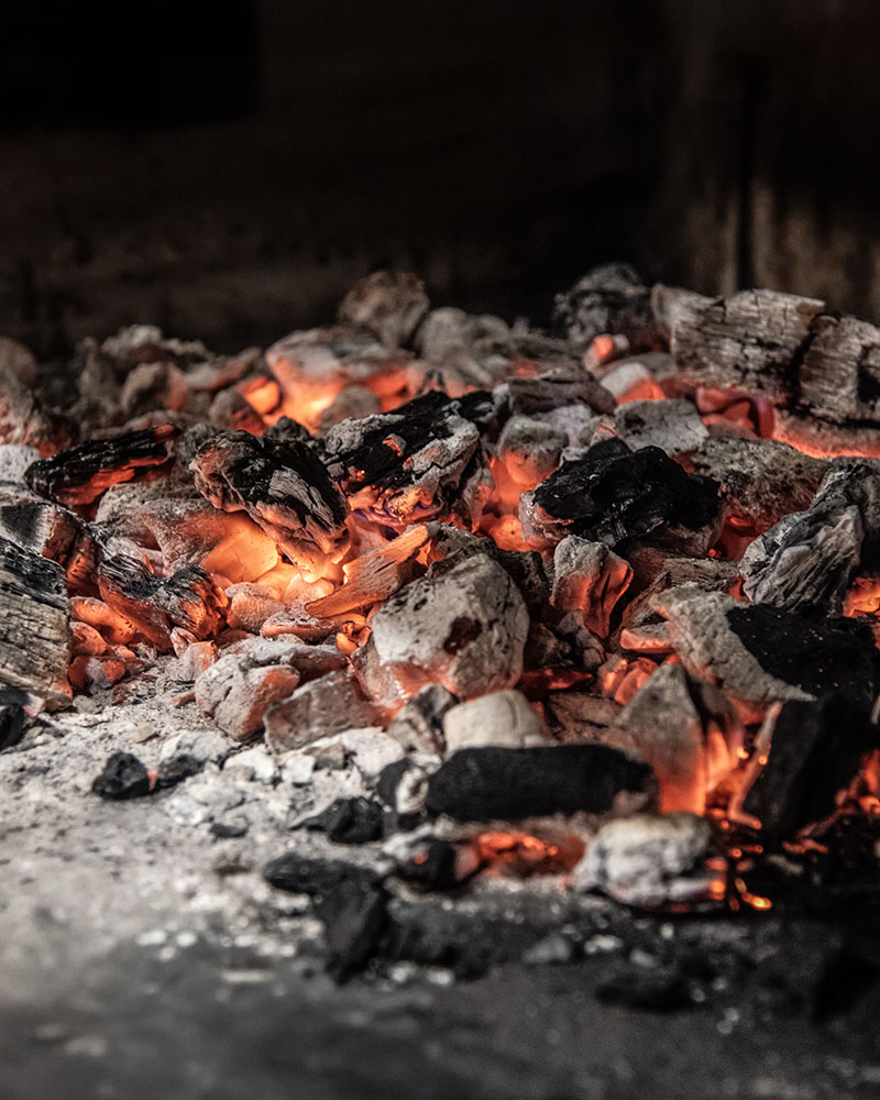Brasas encendidas utilizadas en la preparación del menú tradicional de Navidad en Marmalé con vino Cepa 21