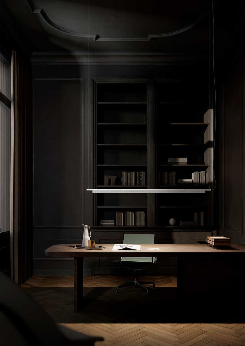 Compendium Suspension Luceplan: despacho en tonos grises oscuros con una estantería de obra en la pared del fondo y justo delante una mesa de madera tipo escritorio grande que tiene varios objetos encima y una silla debajo, sobre la que se encuentra la lámpara Compendium Suspension de Luceplan en color plateado encendida.