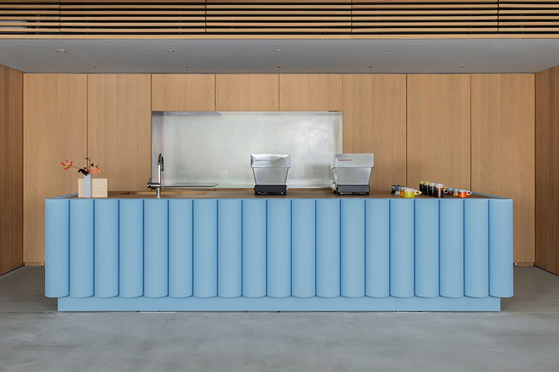 Barra de café en Core de Karimoku con mobiliario en madera y mostrador azul