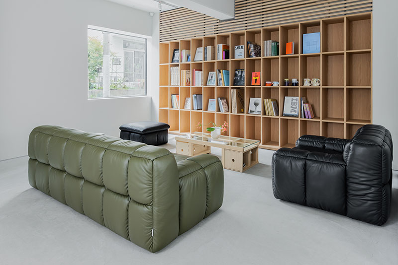 Espacio de lectura en Core de Karimoku con sofás y estantería de madera