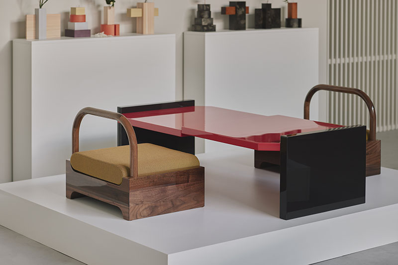 Mesa lacada en rojo y asientos de madera en Core de Karimoku sobre plataforma expositiva