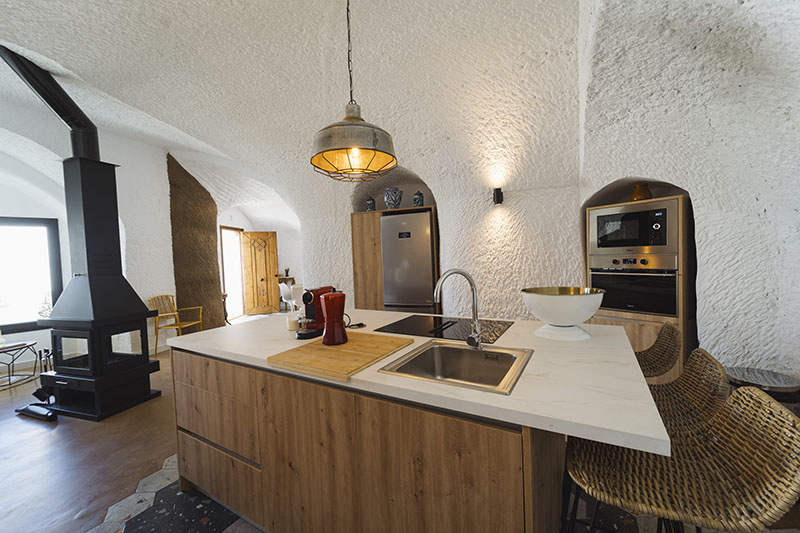 Cocina integrada de Cuevas de Kabila en Granada con isla central y acabado natural