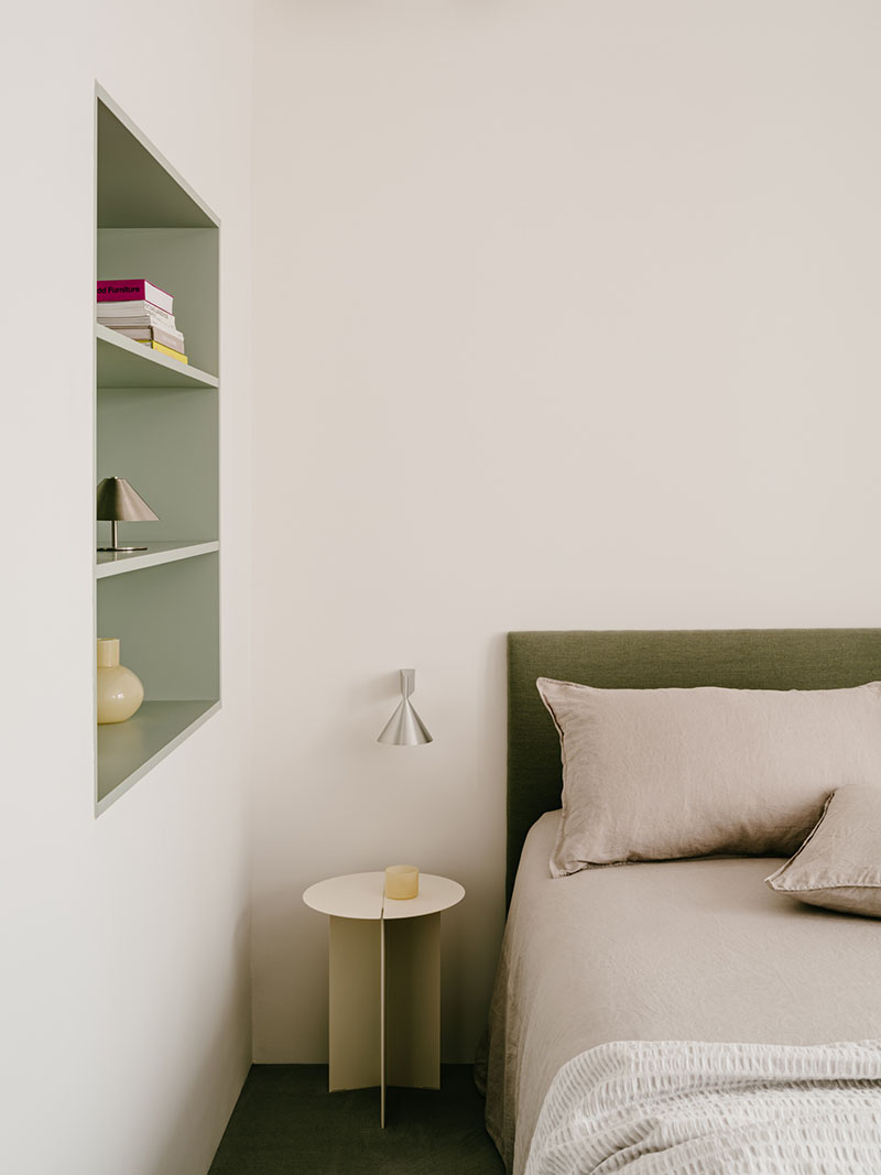 D Iriondo Studio exhibe el dormitorio principal con cabecero tapizado en verde y mesilla de noche