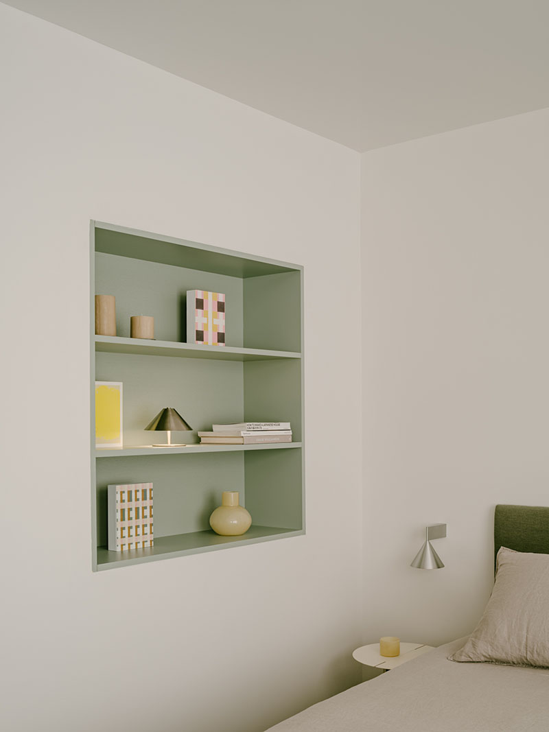 Iriondo Studio incorpora una estantería empotrada en verde salvia con libros y objetos decorativos