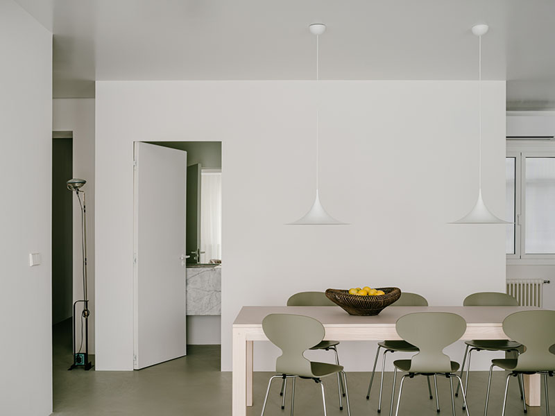 D Iriondo Studio registra el comedor con mesa de madera clara, sillas Ant de Arne Jacobsen y lámparas Semi Pendant de Gubi