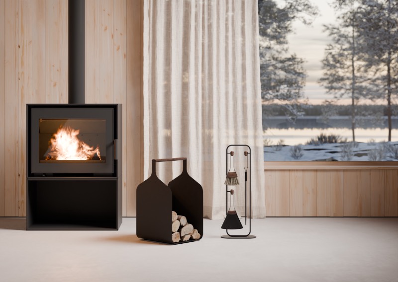 Eldvarm Fumi: espacio acogedor con una chimenea encendida, junto a varias piezas de Eldvarm, de la colección Fumi para leña, delante de una pared de madera clara, junto a una cortina larga blanca y un ventanal por el que se ve un paisaje natural al atardecer.