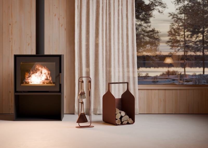 Eldvarm Fumi: espacio acogedor con una chimenea encendida, junto a varias piezas de Eldvarm, de la colección Fumi para leña, delante de una pared de madera clara, junto a una cortina larga blanca y un ventanal por el que se ve un paisaje natural al atardecer.