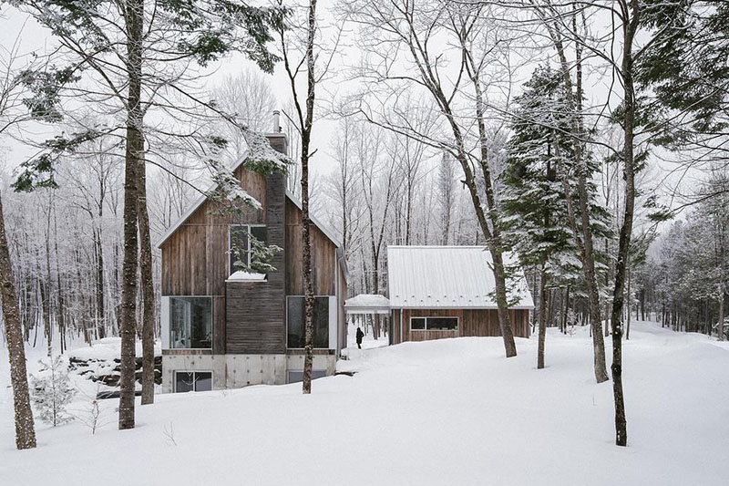 EM architecture muestra la fachada principal del chalet entre nieve y árboles