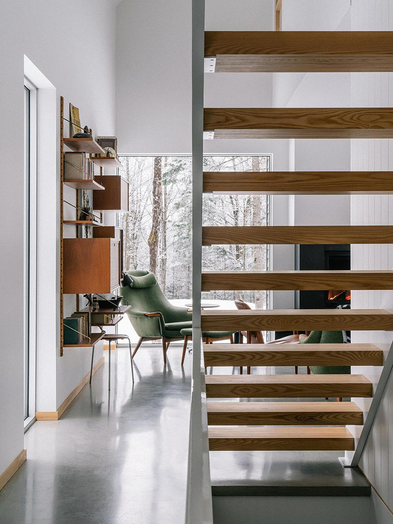EM architecture muestra la escalera de peldaños de madera y la vista hacia la zona de estar
