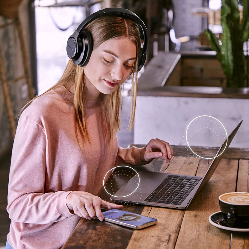 Energy Sistem: una chica con unos headphones usando el portatil y el móvil