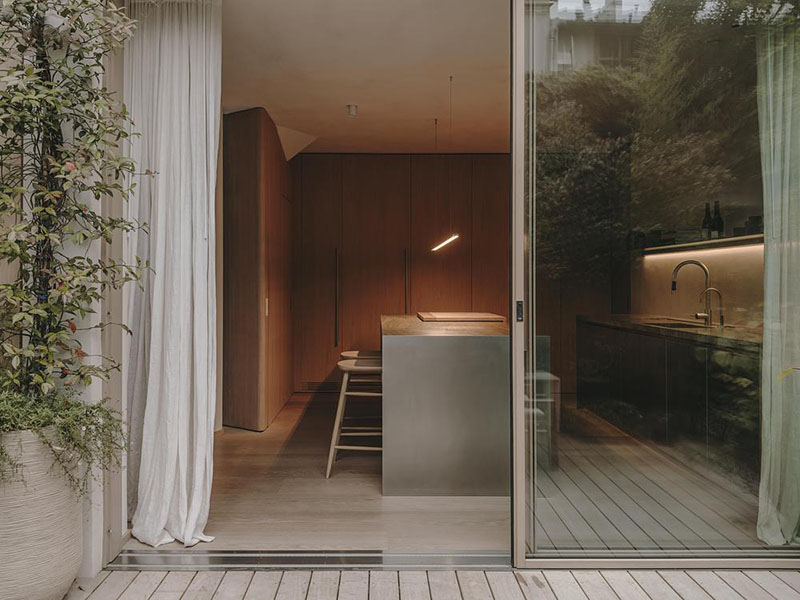 Interiorismo de la Casa en París por Holzrausch que presenta la cocina con isla de acero y acceso al exterior