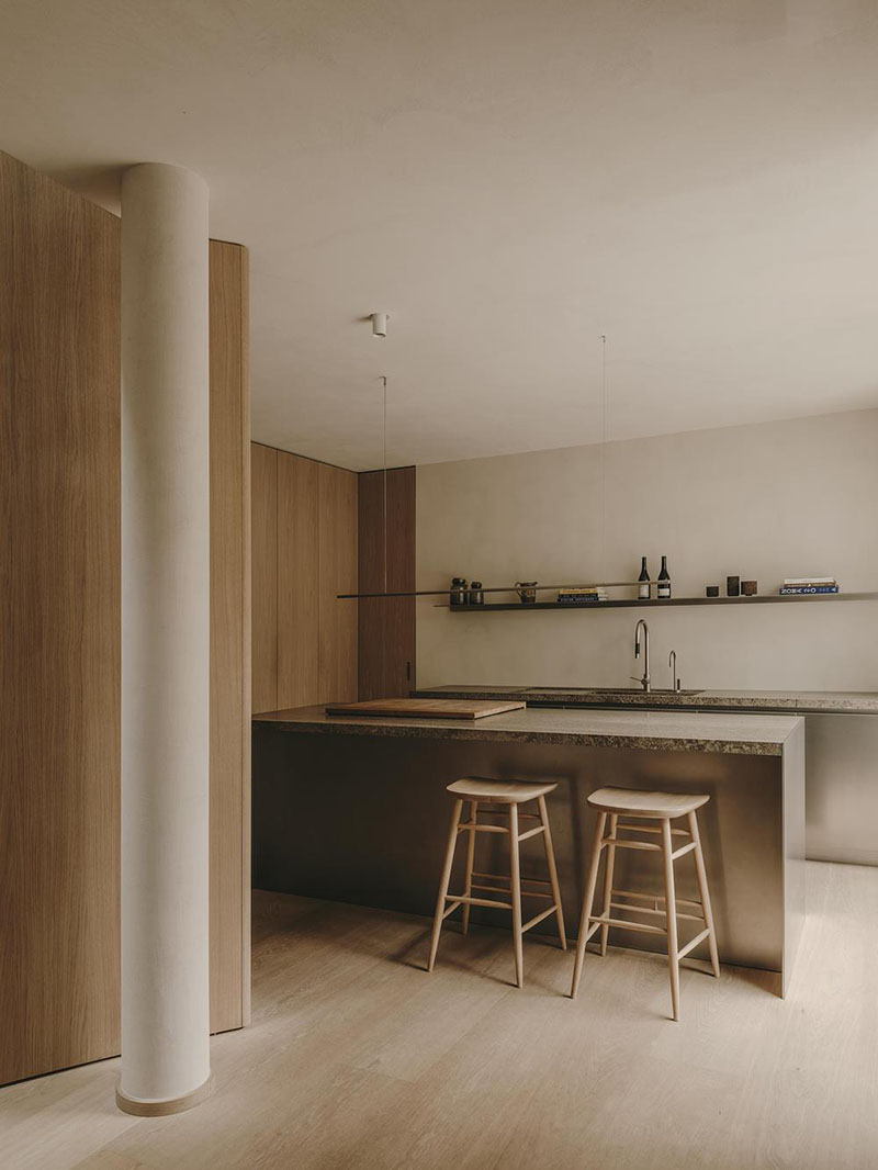 Interiorismo de la Casa en París por Holzrausch que muestra la isla de cocina acompañada por taburetes de madera