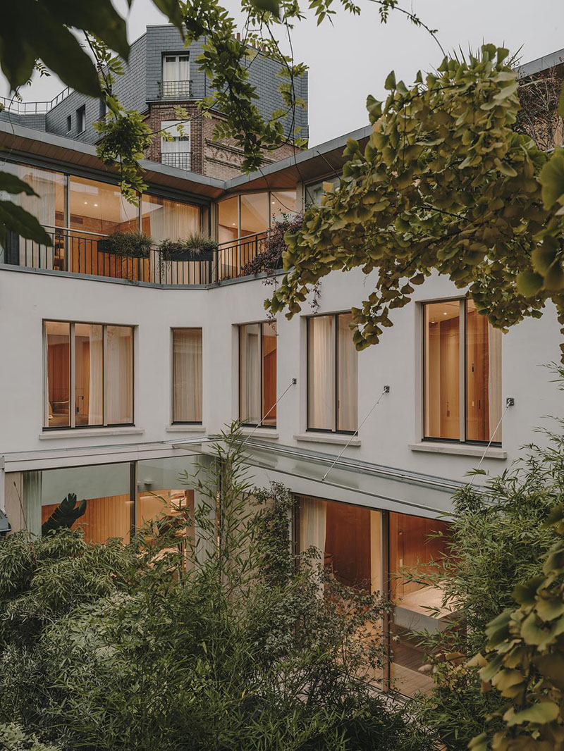 Interiorismo de la Casa en París por Holzrausch que presenta la fachada interior abierta al jardín central