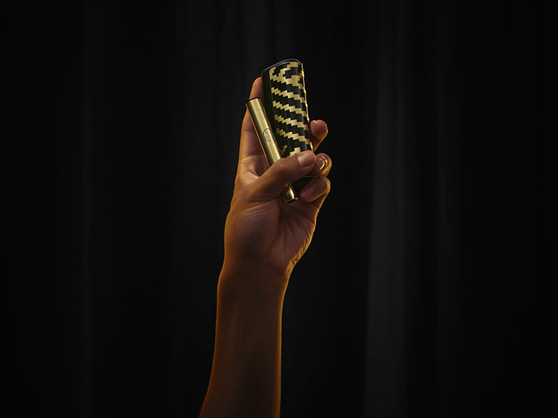 Una mano sostiene dos dispositivos de la edición Iqos Iluma i x Seletti con el patrón en zigzag