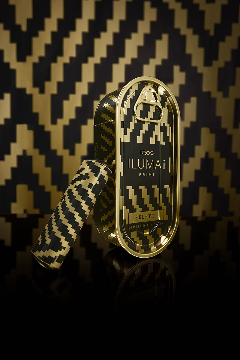 Un estuche y un dispositivo de Iqos Iluma i x Seletti aparecen junto a su embalaje metálico dorado
